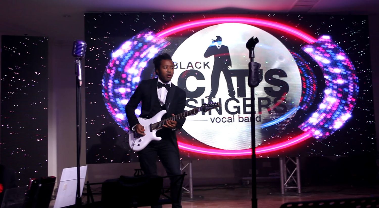 Guitariste devant le logo lumineux Black Cats Singers